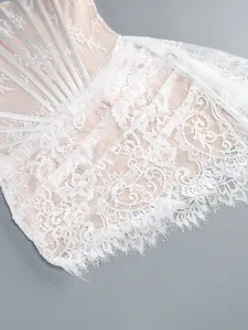 Detailed view of elegant white lace overlay and silver corset ribbons on a formal dress.