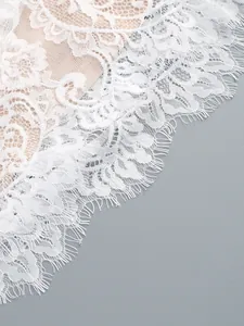 Detailed macro shot of elegant white floral lace fabric with eyelash trim on a dress