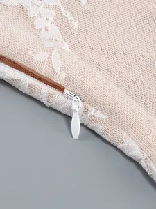 Close-up of invisible zipper on a nude lace dress with intricate white embroidery details.