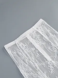 Detailed macro shot of intricate white floral lace fabric on a sheer sexy tube dress