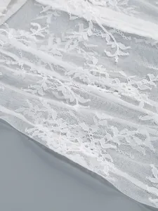 Detailed macro shot of white floral lace fabric with intricate mesh and embroidery patterns