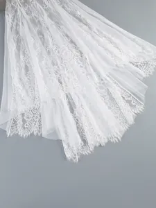 Close-up of intricate white lace and mesh patchwork on female holiday dress skirt