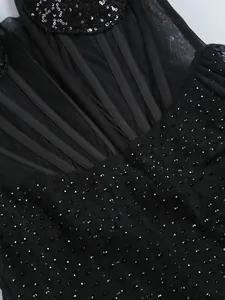 Gros plan d'une robe en résille noire ornée de strass et de paillettes complexes.