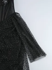 Détail du tissu en tulle noir avec des strass étincelants et des paillettes sur une robe