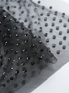 Détail macro du tissu en maille noire avec strass scintillants et motifs à pois élégants