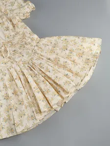Detailed view of the yellow floral pattern and pleated skirt of a short-sleeved mini dress
