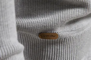 Primo piano del polsino del maglione lavorato a maglia grigio da uomo con patch logo