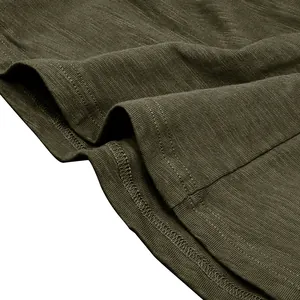 Macro detail of olive green slub cotton fabric and hem stitching on a men's Henley shirt