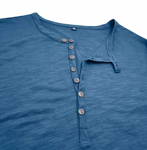 Detailed macro view of a blue slub cotton men's Henley shirt featuring a button placket