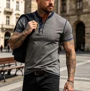 Close-up of a grey short-sleeve Henley T-shirt with navy trim on a model outdoors.