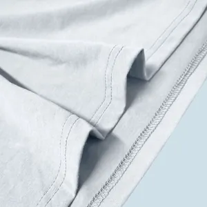 Macro detail of high-quality double-stitched hem on light blue cotton Henley shirt fabric
