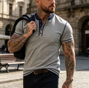 Detail of a grey short-sleeve Henley shirt with navy trim on a tattooed male model