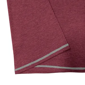 Macro view of contrast grey stitching detail on maroon moisture-wicking men's tee