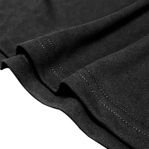 Close-up detail of black polo shirt pique fabric texture and double-stitched hem.
