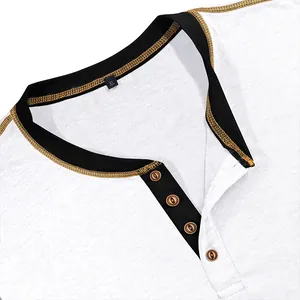 Detail of men's white Henley shirt with black contrast collar and gold stitching.