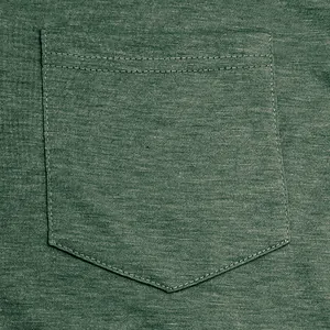 Macro shot of a heather green T-shirt pocket showing fabric texture and stitching.