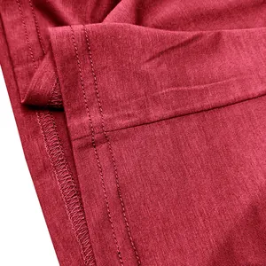 Detailed macro view of the double-stitched hem on a red breathable cotton long-sleeve T-shirt