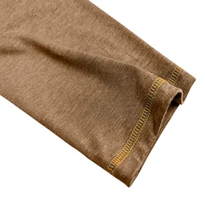 Detailed close-up of brown men's shirt sleeve featuring orange contrast stitching.