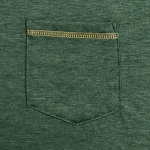 Close-up detail of chest pocket with orange contrast stitching on dark green t-shirt