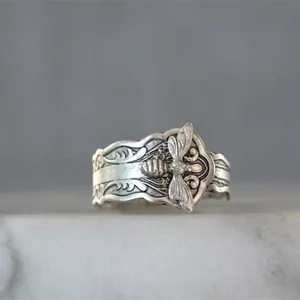 Detailopname van een vintage zilveren ring met een verfijnd bijenmotief en gravures