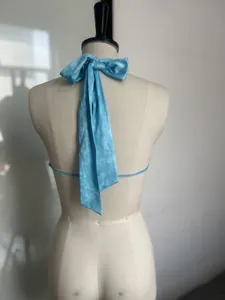 Detailed back view of a light blue halter top featuring a large elegant satin bow tie