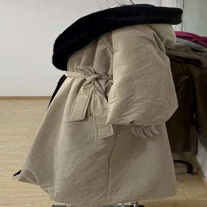 Side view of long beige windbreaker with black fur collar and waist tie detail