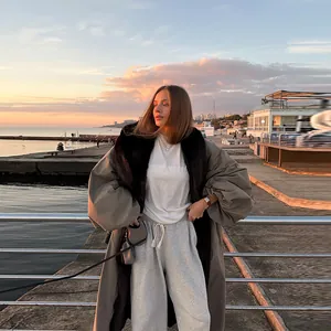 Elegant khaki long trench coat with oversized fur collar and lantern sleeves at sunset.