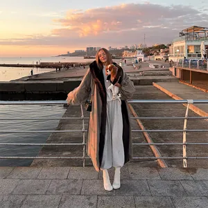 Elegant oversized long windbreaker with a contrast fur collar shown on a coastal walk