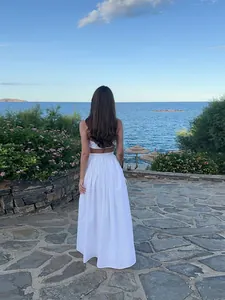 Vue de dos d'un élégant ensemble blanc deux pièces avec crop top et jupe longue en bord de mer