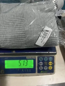 Close-up view of the gray knitted zipper cardigan on a scale weighing 513 grams