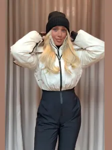 Vue détaillée de la veste de ski blanche stylée et du pantalon de neige noir taille haute