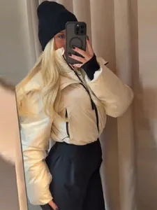 Détail d'un selfie miroir montrant une veste de ski matelassée blanc crème et bonnet