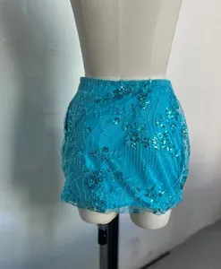 Détail d'une mini-jupe turquoise à paillettes avec broderies florales sur un mannequin blanc