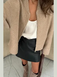 Detailed macro view of the beige ribbed knit texture and metal zipper on oversized cardigan