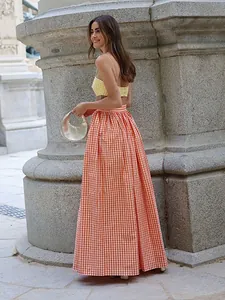 Femme élégante en crop top vichy jaune et jupe longue vichy orange en plein air.