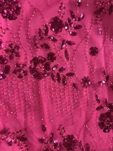 Vue détaillée du tissu en maille rose avec des broderies élégantes de paillettes.