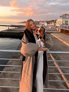Elegant long winter trench coat with contrast fur collar in sunset beach lifestyle setting