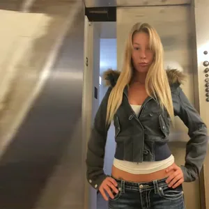 Model trägt eine kurze Vintage-Jeansjacke mit braunem Kunstpelzkragen im Aufzugbereich