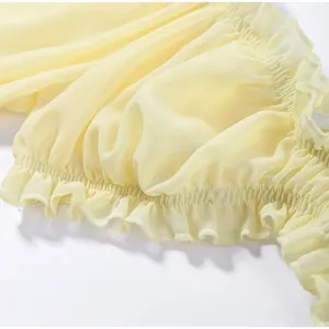 Detail showing yellow ruffled chiffon fabric with smocked elastic waistband