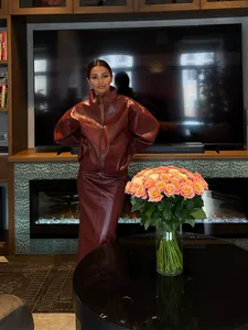 Modisches Model in einem trendigen Set aus burgunderfarbener Kunstlederjacke und Maxirock