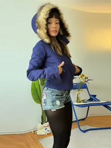 Detailed view of a woman wearing a dark blue vintage short jacket with a faux fur-trimmed hood