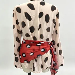 Detailed view of a red polka dot wrap skirt tied over a matching beige shirt