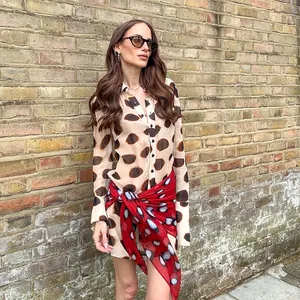 Close-up of a stylish polka dot shirt dress with an elegant red wrap-around tie detail.