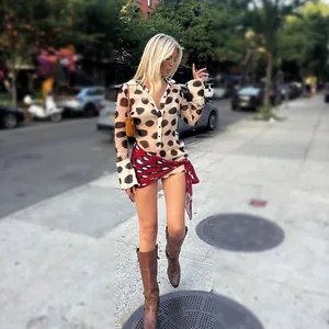 Chic polka-dot long sleeve shirt dress paired with a red patterned wrap skirt on city street