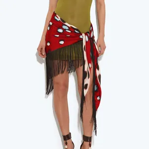 Close-up detail of a vibrant red polka dot wrap skirt featuring elegant black fringe accents