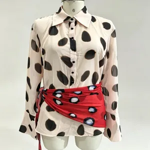 Close-up of a stylish polka dot long sleeve blouse with a red waist tie on mannequin