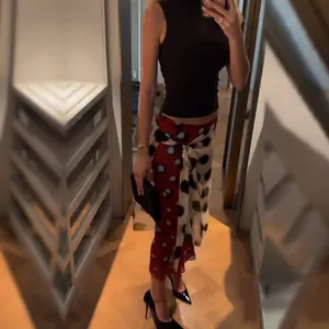 Full body view of a woman wearing a red contrast polka dot wrap midi skirt with side tie