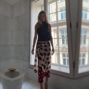 Detailed view of color-block polka dot wrap midi skirt on a model by window