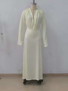 Detailed view of deep V-neck and pleated waist on long sleeve maxi resort dress.