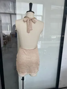 Detailed back view of a champagne gold glittery halter neck knit mini dress with a bow tie